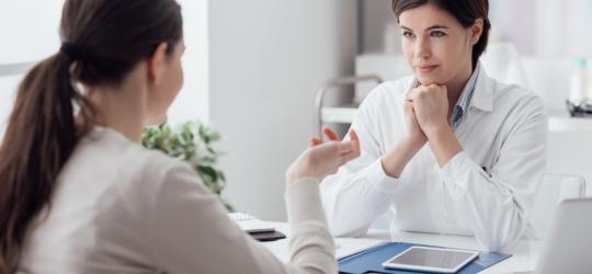 Kobieta podczas konsultacji u lekarki, która podejrzewa u pacjentki hiperandrogenizm.