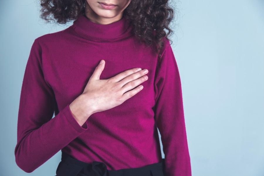 Kobieta trzyma się dłonią za bolesną pierś. Hiperprolaktynemia może objawiać się m.in. bólem piersi.