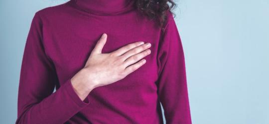 Kobieta trzyma się dłonią za bolesną pierś. Hiperprolaktynemia może objawiać się m.in. bólem piersi.