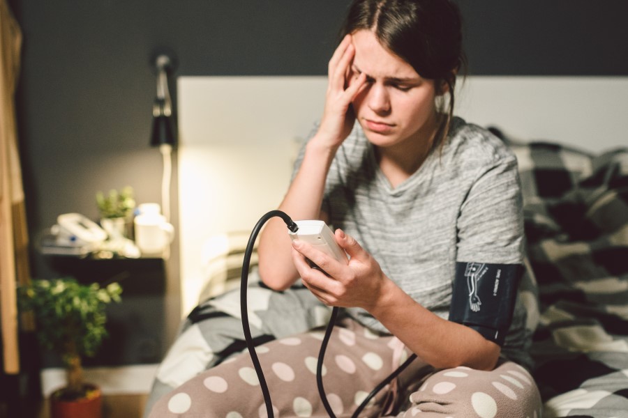 Młoda kobieta używa ciśnieniomierza, dokucza jej hipotonia.