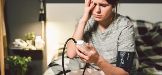 Młoda kobieta używa ciśnieniomierza, dokucza jej hipotonia.
