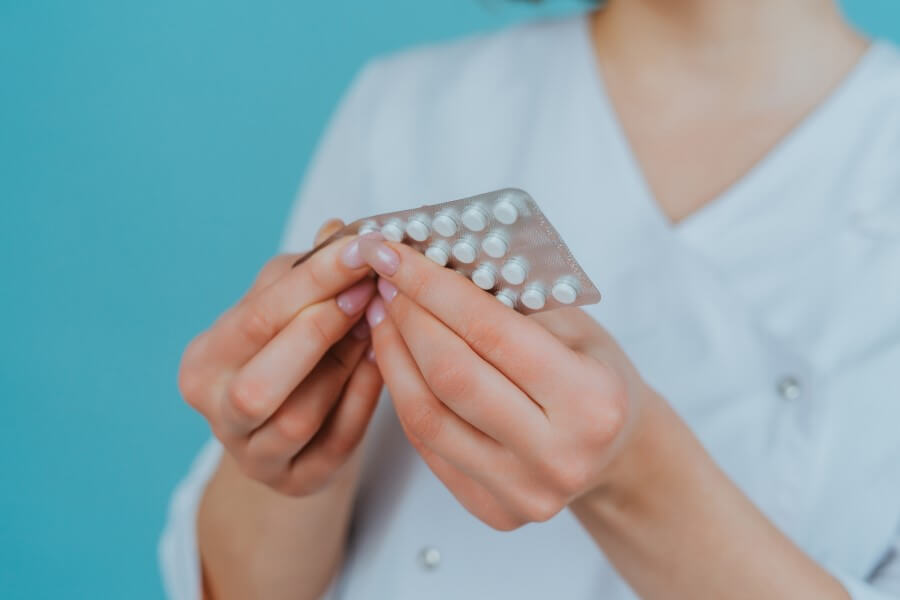 Kobieta wyciąga z blistra tabletkę hydroksyzyny.