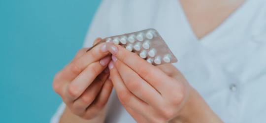 Kobieta wyciąga z blistra tabletkę hydroksyzyny.