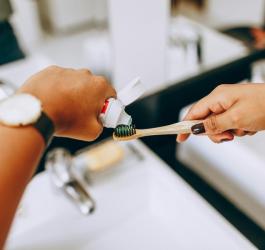 Osoba nakłada pastę do zębów na szczoteczkę.