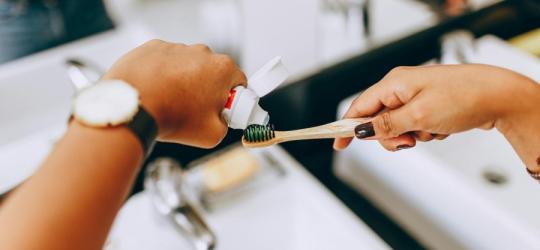 Osoba nakłada pastę do zębów na szczoteczkę.