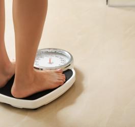 Kobieta stoi na wadze. Lęk przed przyrostem masy ciała to jeden z objawów anoreksji.