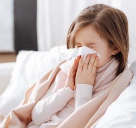 Przeziębiona dziewczynka wydmuchuje nos.