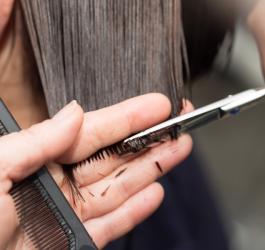 Fryzjer obcina włosy klientki.