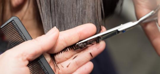 Fryzjer obcina włosy klientki.