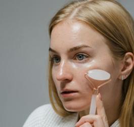 Kobieta wykonuje masaż twarzy przy pomocy rollera.