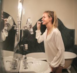 Kobieta szczotkuje zęby przed lustrem.