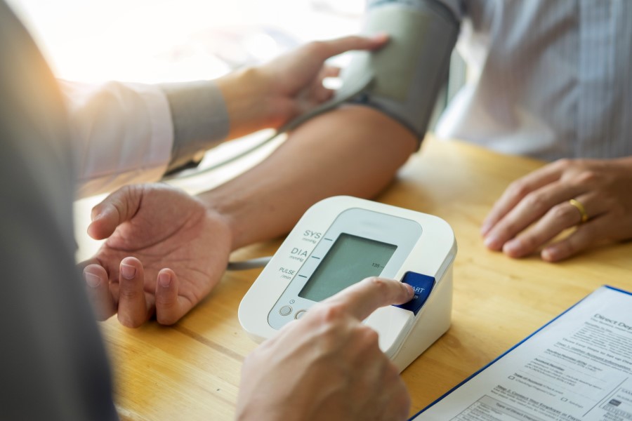 Mężczyzna ma wykonywany pomiar ciśnienia w gabinecie lekarskim.