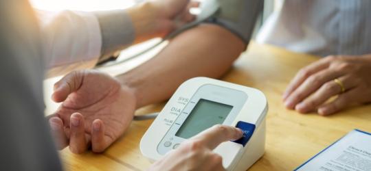 Mężczyzna ma wykonywany pomiar ciśnienia w gabinecie lekarskim.