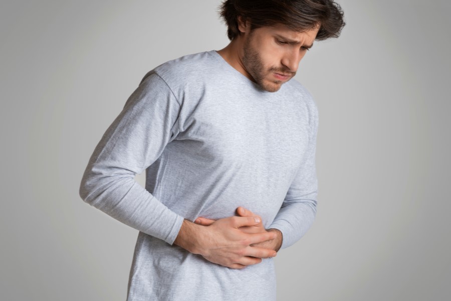 Mężczyzna trzyma się za brzuch, męczy go jelitówka.