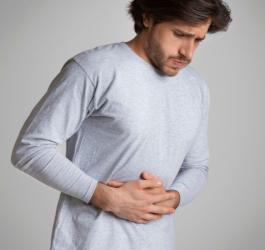 Mężczyzna trzyma się za brzuch, męczy go jelitówka.