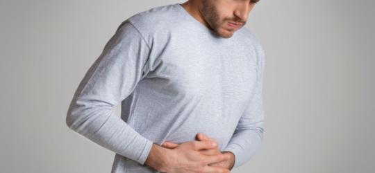 Mężczyzna trzyma się za brzuch, męczy go jelitówka.