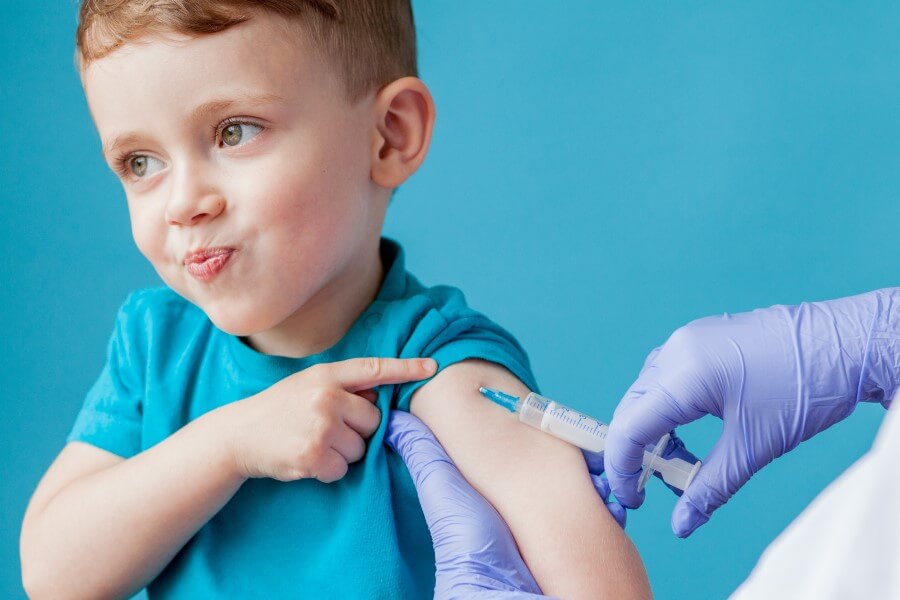 Pewny siebie chłopiec podczas iniekcji szczepionki przez pracownika medycznego.