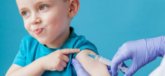 Pewny siebie chłopiec podczas iniekcji szczepionki przez pracownika medycznego.