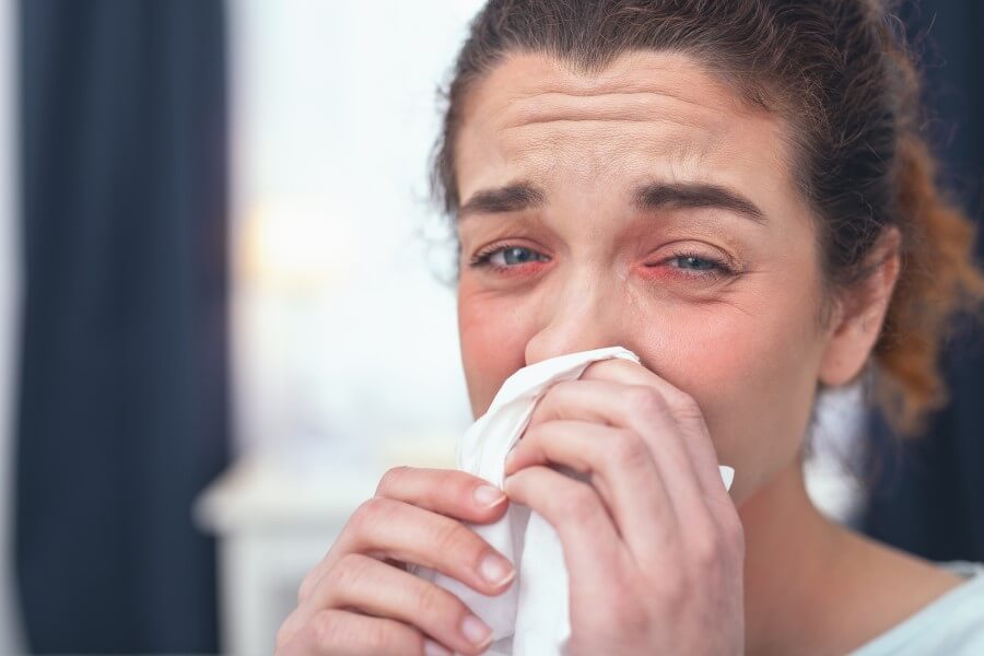 Kobieta wydmuchuje nos, męczy ją katar alergiczny.