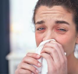 Kobieta wydmuchuje nos, męczy ją katar alergiczny.