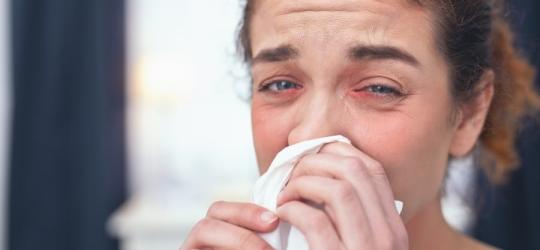 Kobieta wydmuchuje nos, męczy ją katar alergiczny.
