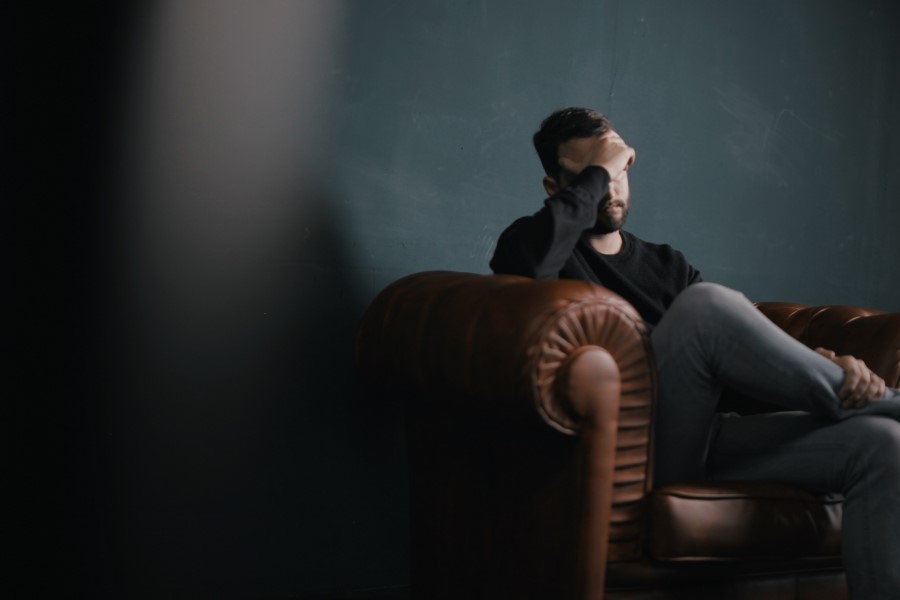 Mężczyzna siedzący na skórzanej kanapie, jest w kiepskiej kondycji psychicznej.