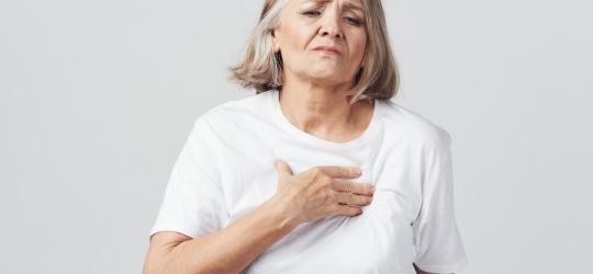 Zmartwiona kobieta trzyma rękę na klatce piersiowej, czuje kłucie w sercu.