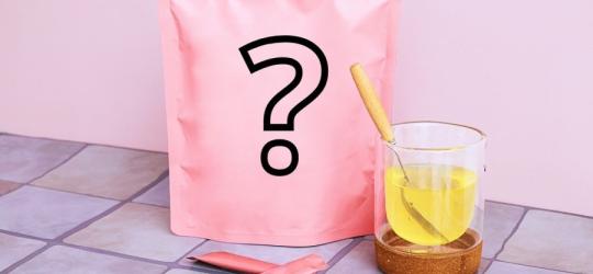 Różowa torebka, saszetki oraz szklanka zawierająca rozpuszczony kolagen.