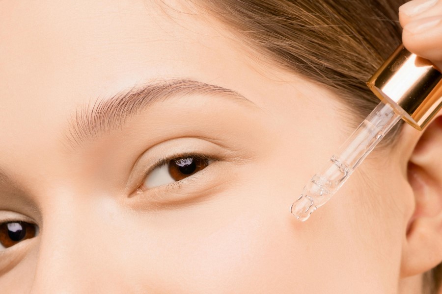 Kobieta nakłada na skórę kosmetyk przy pomocy pipety.
