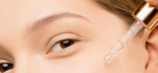 Kobieta nakłada na skórę kosmetyk przy pomocy pipety.