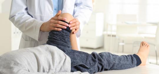 Dziecko w gabinecie ortopedycznym podczas diagnostyki koślawości kolan.