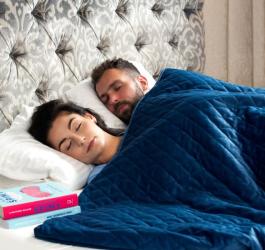 Kobieta i mężczyzna śpią w łóżku, leżą pod kołdrą obciążeniową.