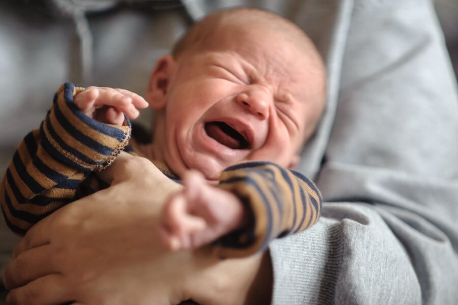 Dziecko płacze z powodu bolesnej kolki niemowlęcej.