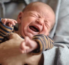 Dziecko płacze z powodu bolesnej kolki niemowlęcej.