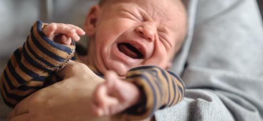 Dziecko płacze z powodu bolesnej kolki niemowlęcej.
