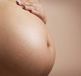 Kobieta trzyma rękę na ciążowym brzuszku.