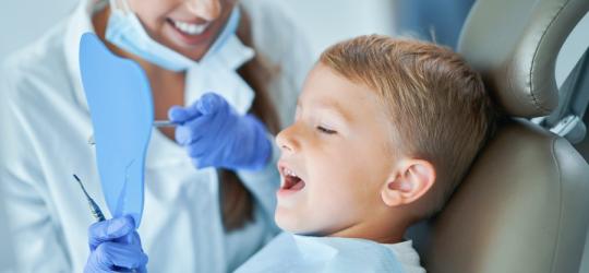 Dziecko u stomatologa przez lakowaniem zębów.