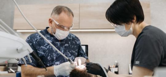 Stomatolog, higienistka stomatologiczna i pacjent podczas leczenia stomatologicznego.