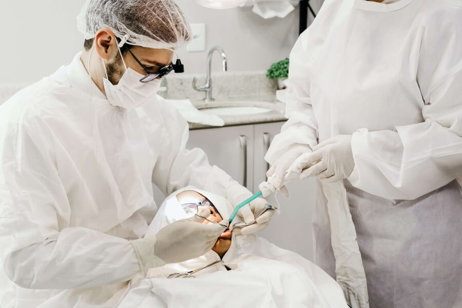 Stomatolog wykonuje u pacjenta leczenie kanałowe przy asyście higienistki stomatologicznej.