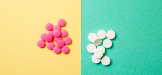 Białe i różowe leki na cholesterol na żółto-zielonym tle.