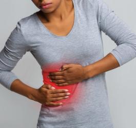 Kobieta trzyma się za bolesny bok, powinna wykonać badanie lipazy.