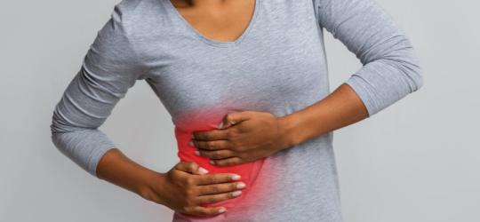 Kobieta trzyma się za bolesny bok, powinna wykonać badanie lipazy.