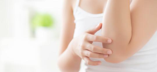 Kobieta sprawdza kondycję skóry na przedramionach.