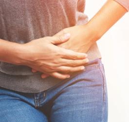 Kobieta trzyma się za podbrzusze, cierpi na dolegliwości ze strony układu rozrodczego.