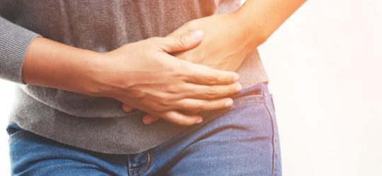 Kobieta trzyma się za podbrzusze, cierpi na dolegliwości ze strony układu rozrodczego.