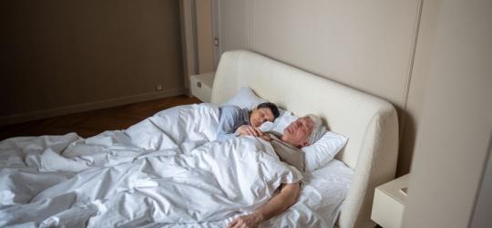 Starsza para śpi w swoim łóżku.