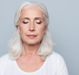 Starsza kobieta przymyka powieki, ma mroczki przed oczami.