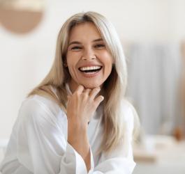 Zadowolona, roześmiana kobieta spogląda w kierunku fotografa.