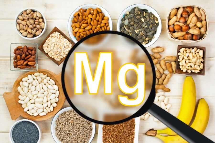 Źródła magnezu (nasiona, orzechy, kasze, strączki i owoce) ułożone z miseczkach.