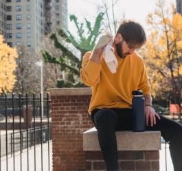 Mężczyzna siedzi na murku, dokucza mu nadmierna potliwość.